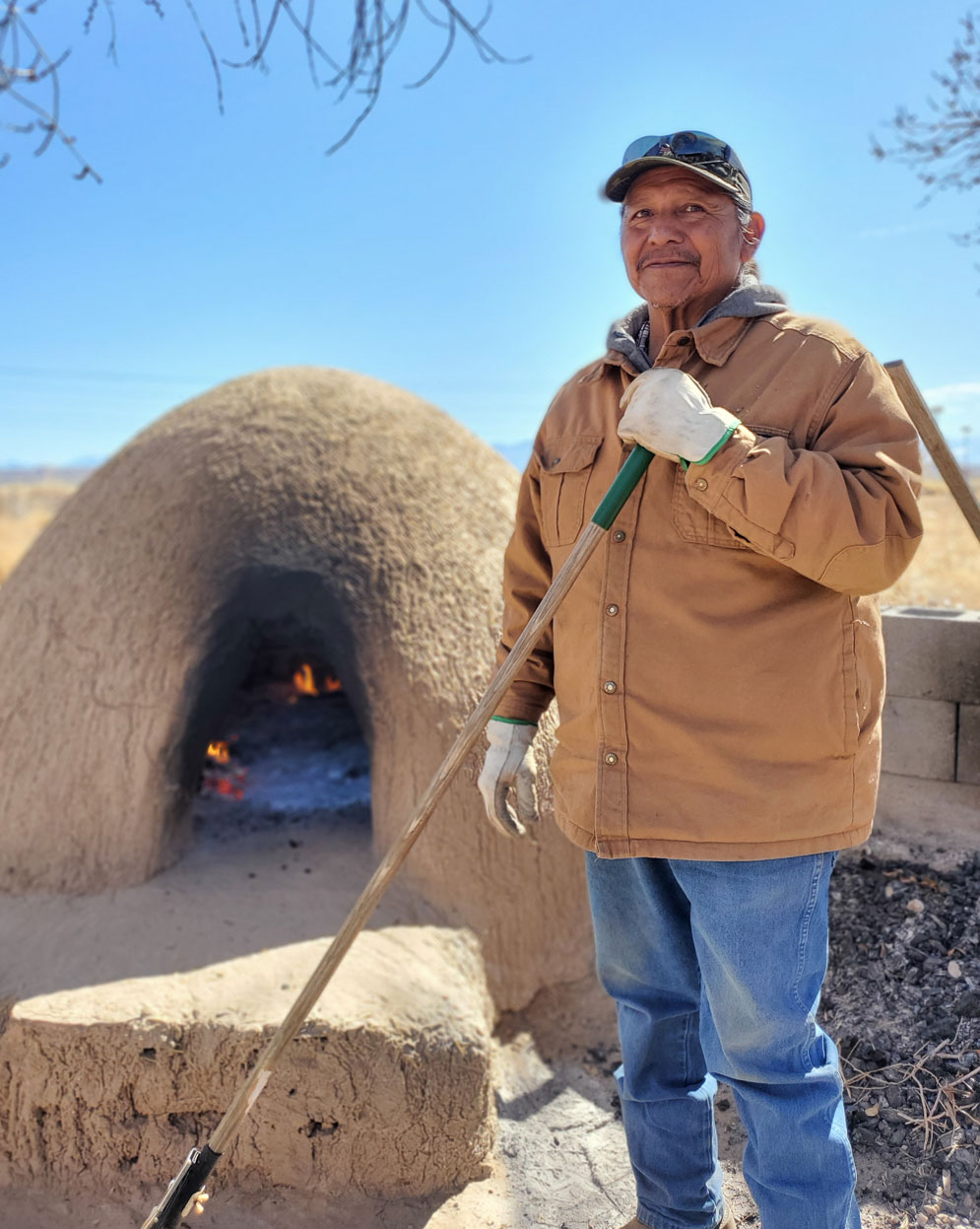 Man baking in horno oven in Okay Owingeh Pueblo in Northern New Mexico. 