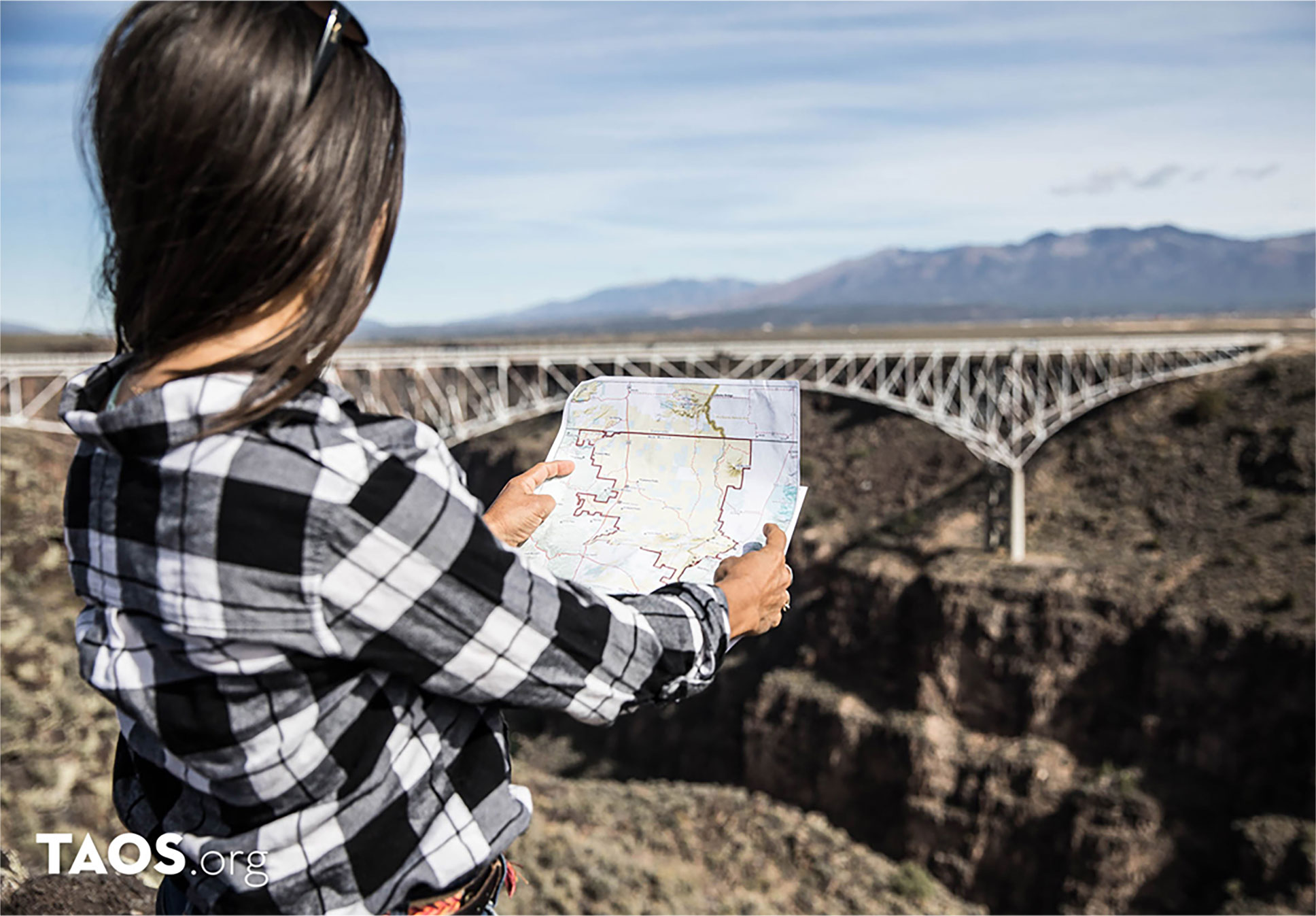 Heritage Inspirations guide holding a map at the Rio Grande Gorge Bridge in Taos, New Mexico.