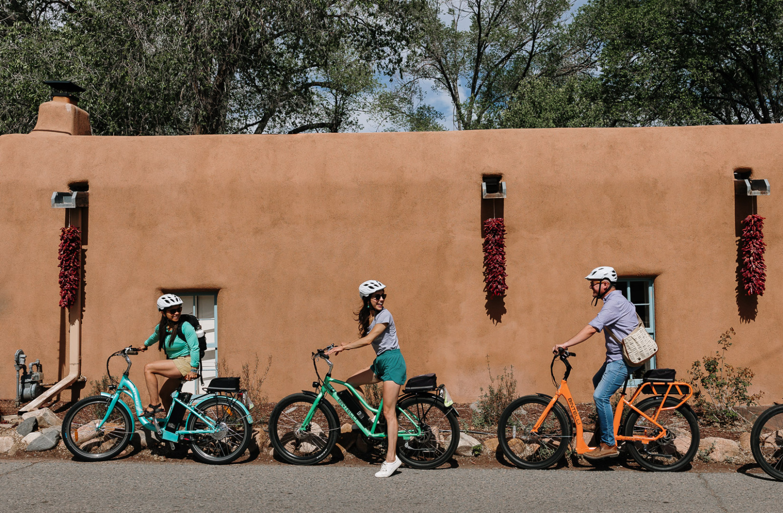 Three E-Bike guests in front of ristras in Santa Fe, New Mexico.